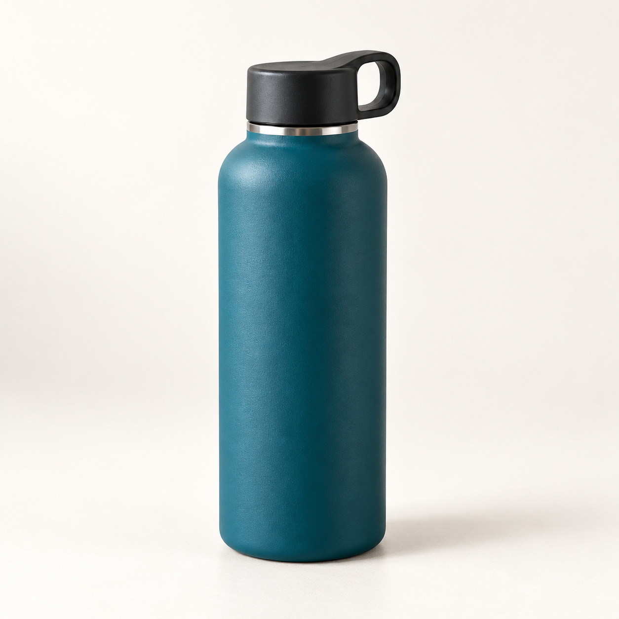 Botol rekaan teal pada latar studio putih hangat dengan bayangan lembut di bawahnya.