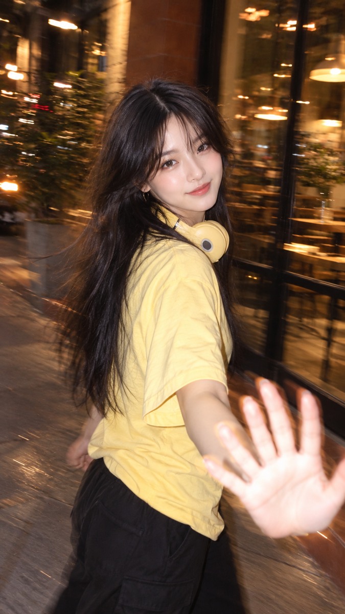 Model yang sama pada malam hari, tangan dekat lensa terkena flash dan lampu latar membentuk jejak blur.